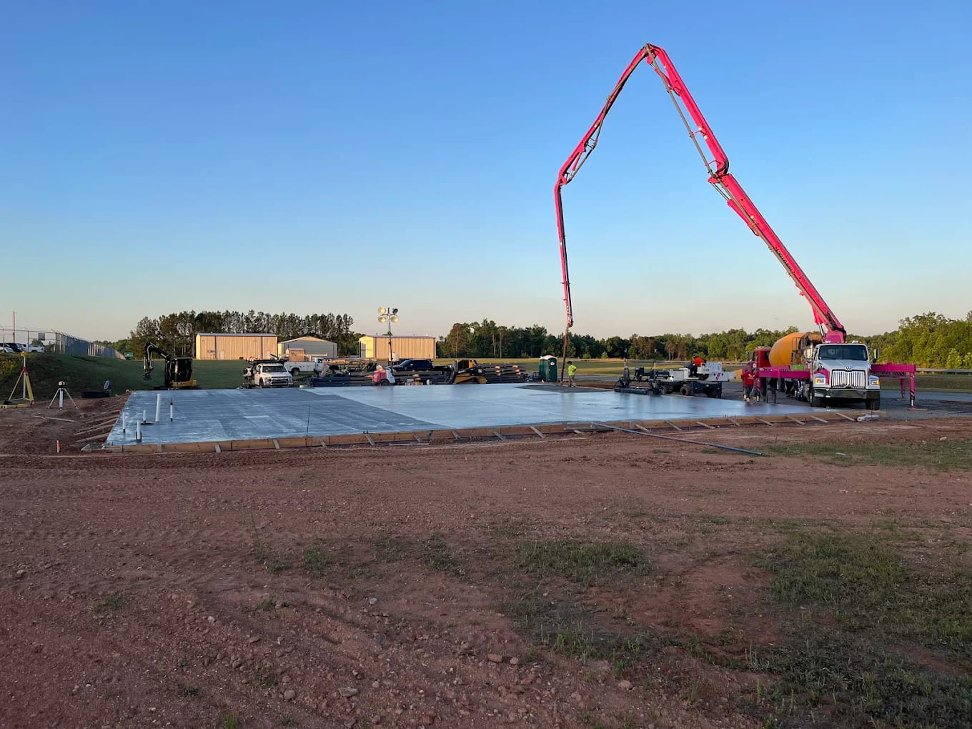 Concrete pump truck pouring a commercial slab at dawn